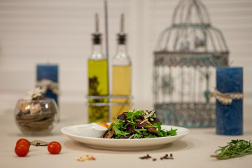 Meat, fish, salads on the table in white plate in the interior with olive oil