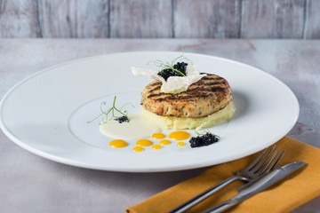 Fish cutlets garnished with potato puree on a white plate yellow deops from sauce. prepared by chef