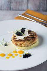 Fish cutlets garnished with potato puree on a white plate yellow deops from sauce. prepared by chef