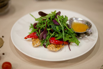 Meat, fish, salads on the table in white plate in the interior with olive oil
