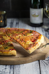 Hawaiian pizza with pineapple on old wooden table, rustic still life style.