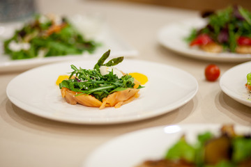 Meat, fish, salads on the table in white plate in the interior with olive oil