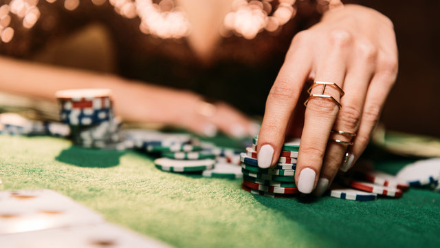 cropped image of girl playing poker and taking chips at table in casino