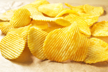 Potato chips heap on wrapping paper, close-up