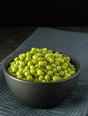 A bowl of fresh peas on a dark cloth background with copy space for your text