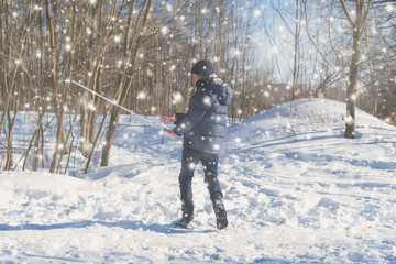 Teen boy on skis in the park in the winter snowfall.