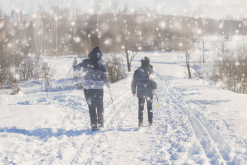Fototapeta na wymiar Two teen boys walk with ski in the park in the winter snowfall. Concept of friendships.