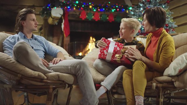 Brother and mother talks to boy holding gifts on Christmas