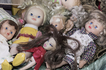 Many creepy dolls on a toy bed