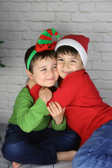 niños felices abrazados en navidad disfrazados de duende y Santa Claus 