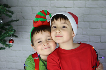 niños felices abrazados en navidad disfrazados de duende y Santa Claus 