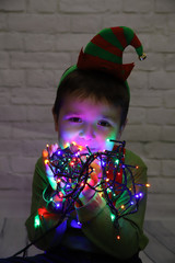 ni&ntilde;o disfrazado de duende con una guirnalda de luces enrollada 