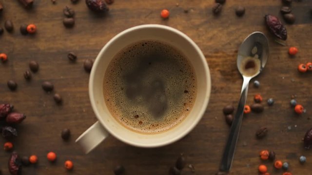 Top view of coffee cup and spoon on a table decorated with berries, rustic retro toned
