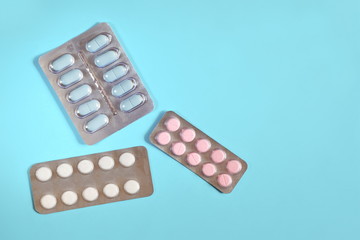 Blisters of different pills on blue background. Copy space for text