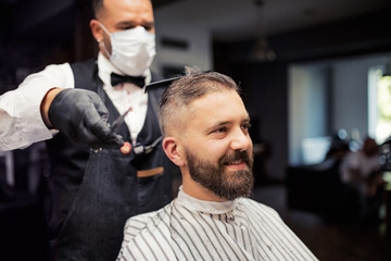 Hipster man client visiting haidresser and hairstylist in barber shop.
