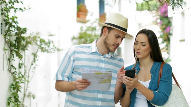 Couple of tourists booking hotel online on smart phone and finding best offer in the street