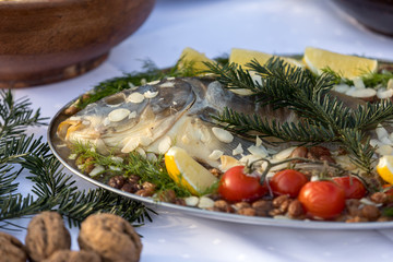 carp with lemon, almonds and cherry tomatoes on the plate