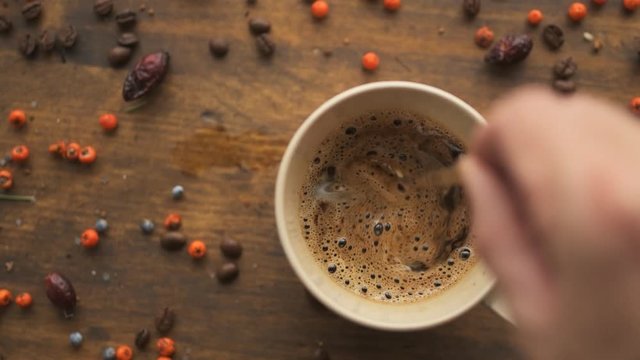 Male hand steering coffee in a cup with spoon, slow motion