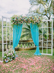 Wedding Arch with flowers, petals and blue cloth. Wedding ceremony.
