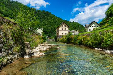 Fototapeta na wymiar Sunny alpine village and clear mountain stream.