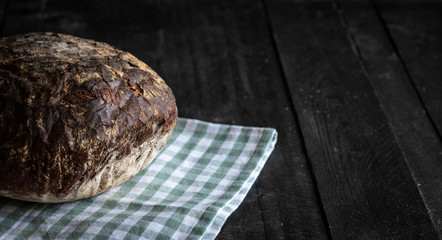 Fresh rye bread on black wooden table