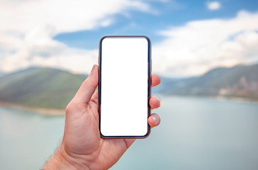 Hand of holding smartphone with white screen on nature background