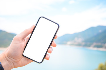 Hand of holding smartphone with white screen on nature background