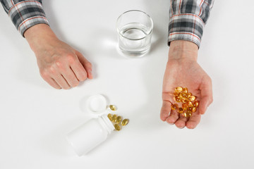 Obraz premium Man hand holds yellow medication capsules of omega 3