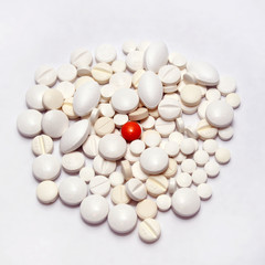 Fototapeta na wymiar A scattering of different white pills on a white background, one orange pill