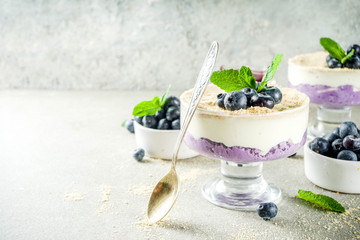 Sweet summer dessert, Blueberry no baked inverted cheesecake in glass, grey stone background copy space