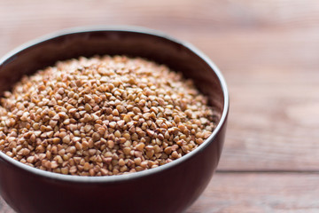 buckwheat in a bowl on a wooden background, selective focus