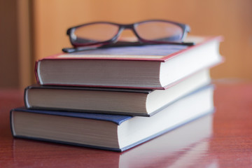 a stack of several books and glasses on the table