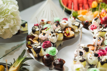 Delicious and tasty dessert table with cupcakes shots at reception closeup