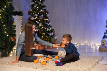 mom and son eat at Christmas tree with lights