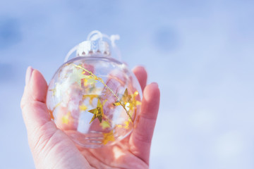 Christmas magic Ball,  Waiting for the Christmas, Magic Atmosphere. Transparent glass Christmas ball with gold stars in female hand on snow winter background.