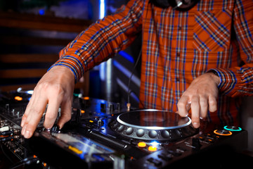 Dj mixes the track in the nightclub at party. In the background laser light show