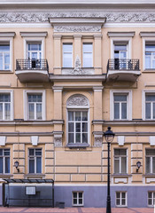 Vintage architecture classical facade. Building with balconies and arch window. Public transport stop. Front view close up.