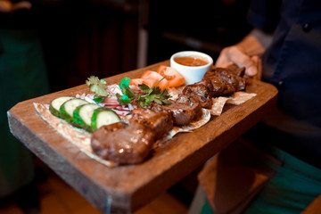 Bbq meat on wooden skewers on plate, top view.