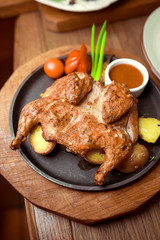 Butterflied roasted chicken with lemon, tomatoes and rosemary herbs on rustic wooden table, delicious Thanksgiving or Sunday dinner