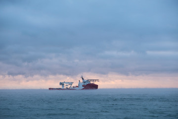 Obraz premium Ship loading pipeline into the sea. Beautiful sea view at sunset.
