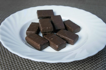 Chocolate candies on a white plate. Concept of unhealthy eating.