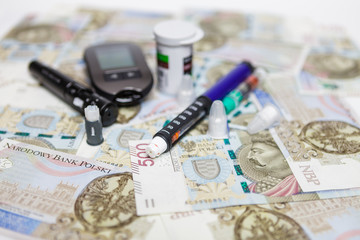 Lancet with spare needles, glucometer, strips, box of spare strips, pen injector, spare insulin and pen needles on polish money banknotes 500 PLN