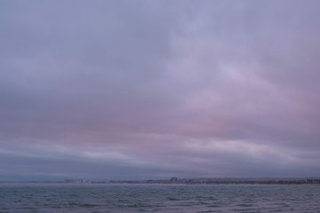 Mist and fog over the sea. Beautiful seascape with pink sunset and coastal town.