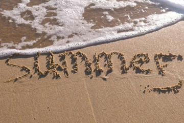Fototapeta premium Word Summer written in the sea sand. Waves washed away the inscription.