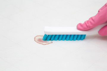 Dry cleaner's employee hand in rubber protective glove removing fresh or old blood stain from white...