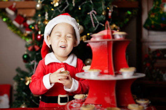 toddler baby girl enjoying  Christmas mince pie  in front of christmas tree