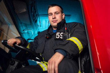 Photo of fireman man sitting in cab of fire truck