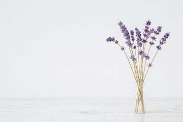 Dried purple lavender in vase on table at light gray wall. Mockup for positive idea. Empty place...