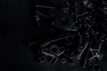 Abstract of Used Metallic knot screw nuts and nail bolts on dark background