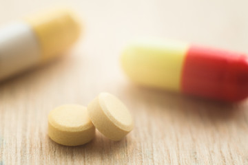 Selective focus on pill spread on wooden background with shadow. Global healthcare concept. Pharmaceutical industry.